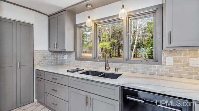 kitchen with dishwasher, gray cabinets, light stone counters, and a sink