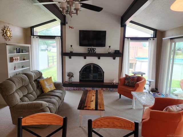 carpeted living area with vaulted ceiling, a glass covered fireplace, a textured ceiling, and a ceiling fan