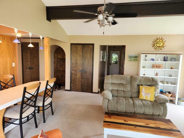 living area featuring arched walkways, a ceiling fan, vaulted ceiling with beams, and light carpet