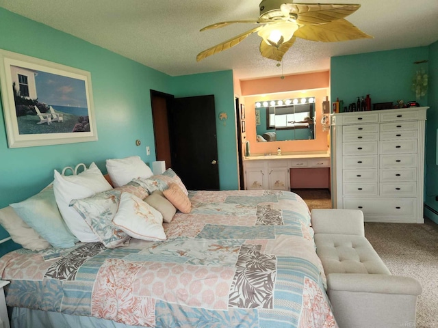 carpeted bedroom with a sink, a ceiling fan, a textured ceiling, and ensuite bathroom
