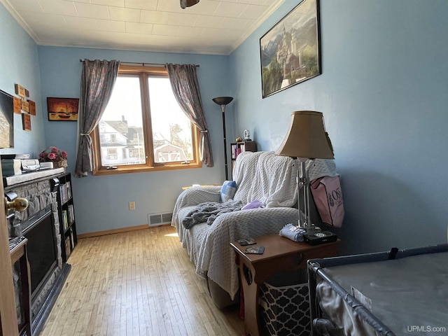 bedroom with light wood finished floors, baseboards, visible vents, and ornamental molding