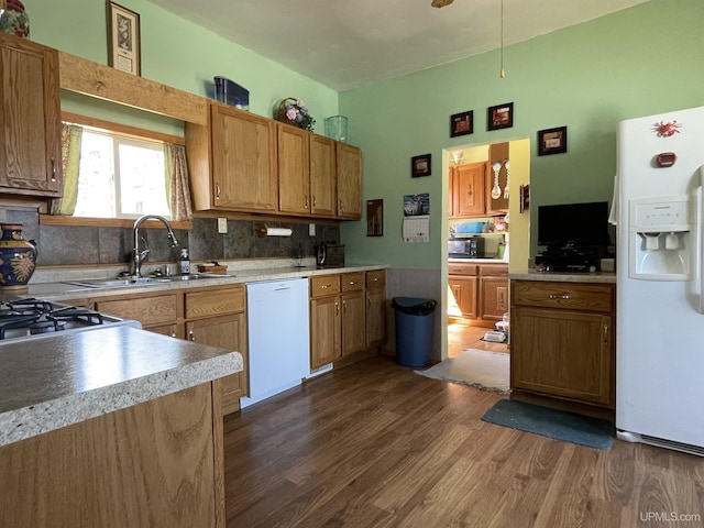 kitchen with a sink, dark wood finished floors, decorative backsplash, white appliances, and light countertops