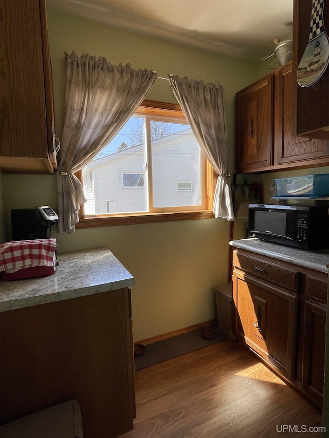 kitchen featuring black microwave, wood finished floors, and baseboards