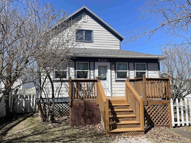 view of front of house with fence, a deck, and a shingled roof