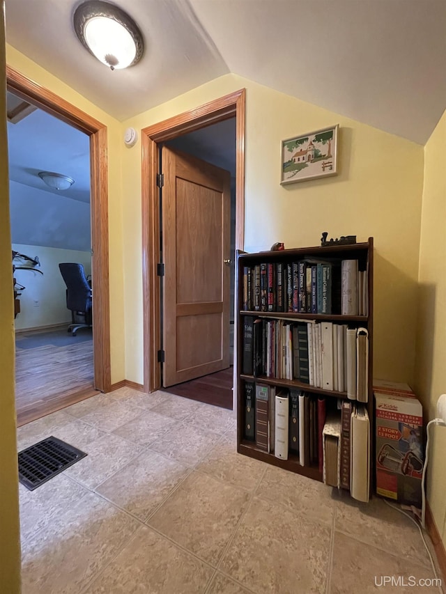 corridor featuring baseboards, vaulted ceiling, and visible vents