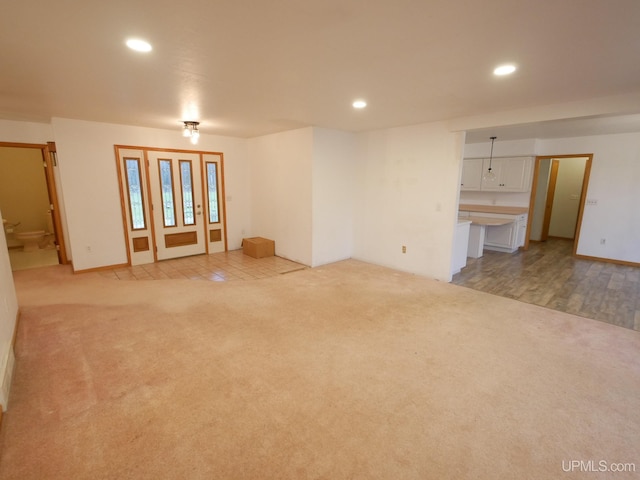 unfurnished living room featuring recessed lighting, baseboards, and light carpet