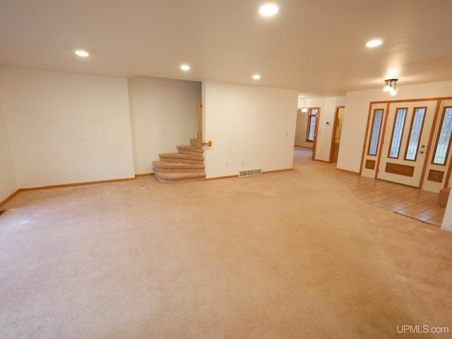 below grade area with light carpet, baseboards, visible vents, recessed lighting, and stairs