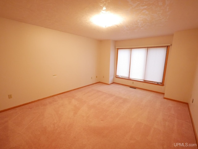 spare room featuring visible vents, baseboards, and light carpet
