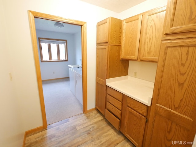 interior space featuring light countertops, light brown cabinets, washing machine and dryer, light wood-style floors, and baseboards