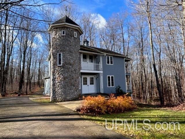 view of front of home featuring french doors, a chimney, and a balcony