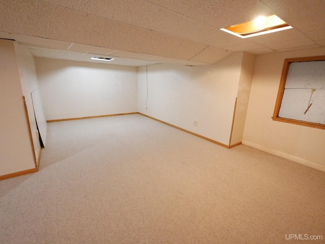 finished basement with a paneled ceiling, baseboards, and carpet floors