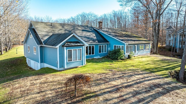 view of front of home with a front yard, roof with shingles, and a chimney