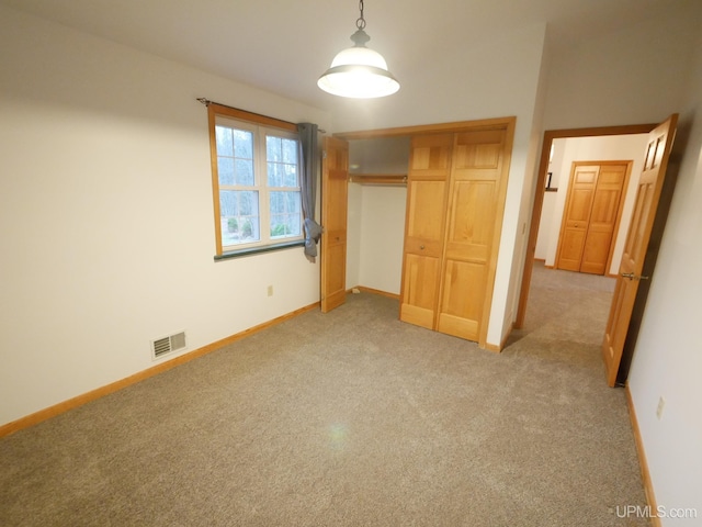 unfurnished bedroom with light carpet, a closet, visible vents, and baseboards