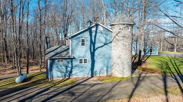 view of side of home with a chimney and a shingled roof