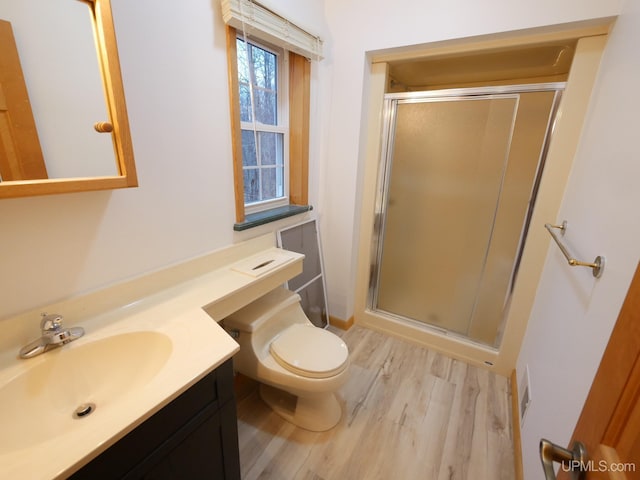 full bath with a shower stall, toilet, vanity, and wood finished floors