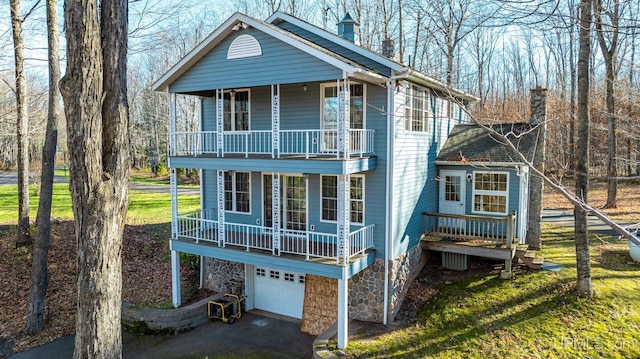 view of front of house featuring a porch, aphalt driveway, a balcony, and a garage