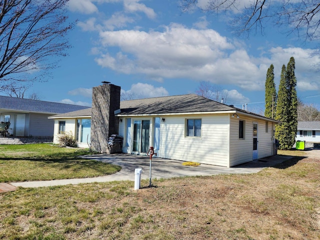 view of front of house with a front lawn, a patio, and a chimney