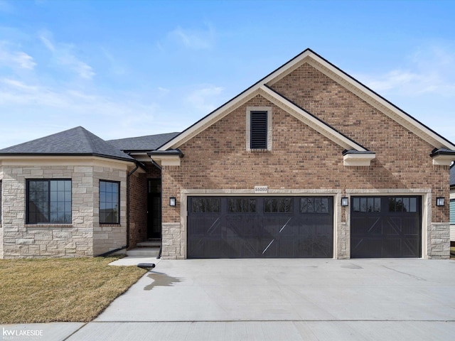 view of front facade with stone siding, a shingled roof, and driveway