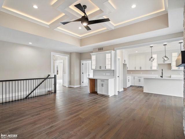 unfurnished living room with dark wood finished floors, coffered ceiling, visible vents, a ceiling fan, and baseboards