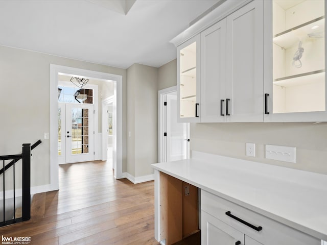 kitchen with light countertops, light wood-style flooring, baseboards, and white cabinetry