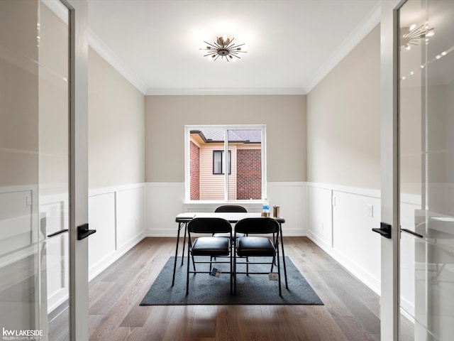dining room with crown molding, french doors, wood finished floors, and a wainscoted wall
