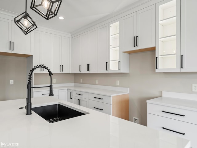 kitchen with a sink, recessed lighting, white cabinetry, glass insert cabinets, and light countertops