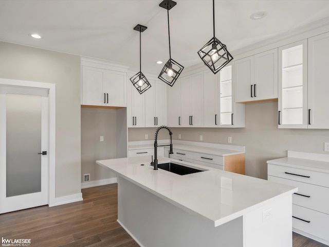 kitchen featuring recessed lighting, a sink, dark wood-style flooring, a center island with sink, and white cabinetry