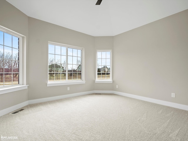 empty room featuring baseboards, visible vents, carpet floors, and ceiling fan