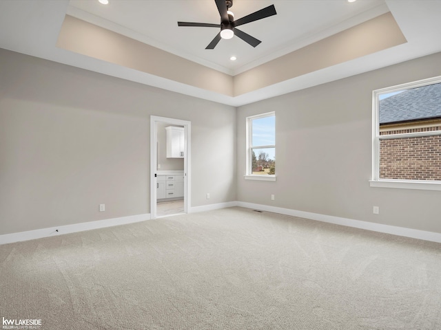 empty room with light carpet, a tray ceiling, baseboards, recessed lighting, and ceiling fan