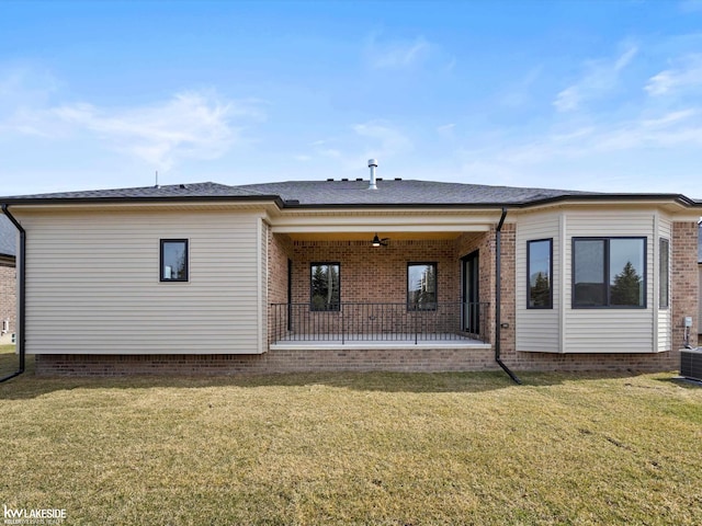 rear view of house featuring a lawn, brick siding, and a patio