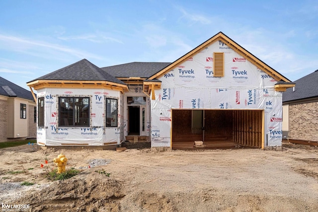 unfinished property featuring driveway and a shingled roof