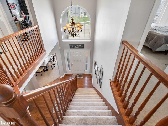 foyer with baseboards, a notable chandelier, wood finished floors, a high ceiling, and stairs