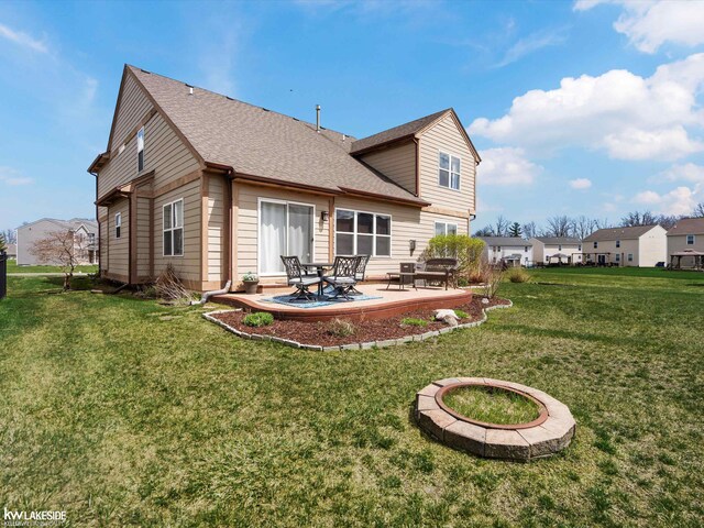 rear view of house featuring roof with shingles, a yard, and a patio