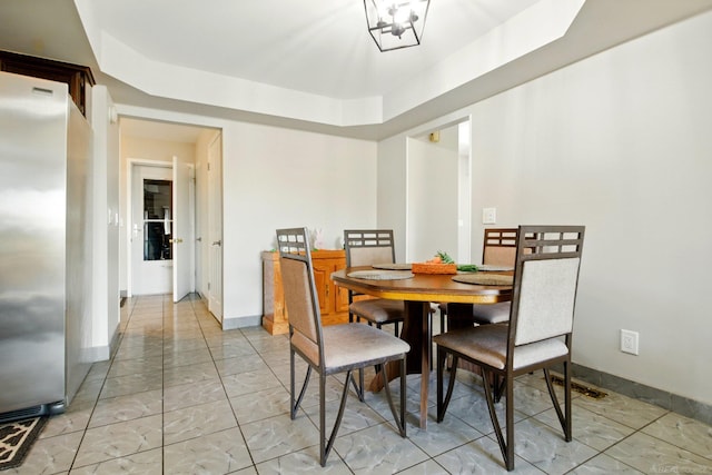 dining area featuring a tray ceiling, a chandelier, marble finish floor, and baseboards