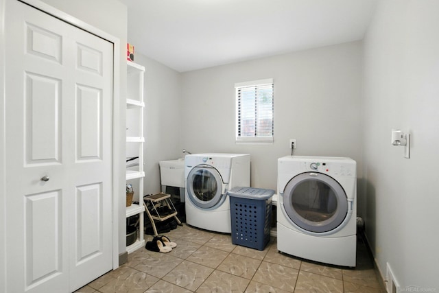 clothes washing area featuring light tile patterned floors, separate washer and dryer, and laundry area