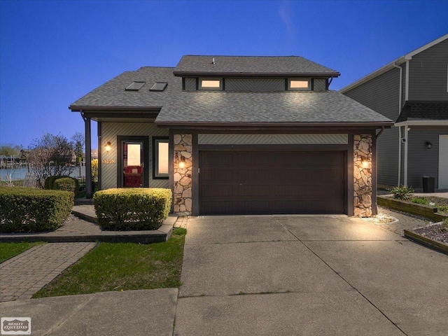 view of front facade with an attached garage, driveway, stone siding, and roof with shingles