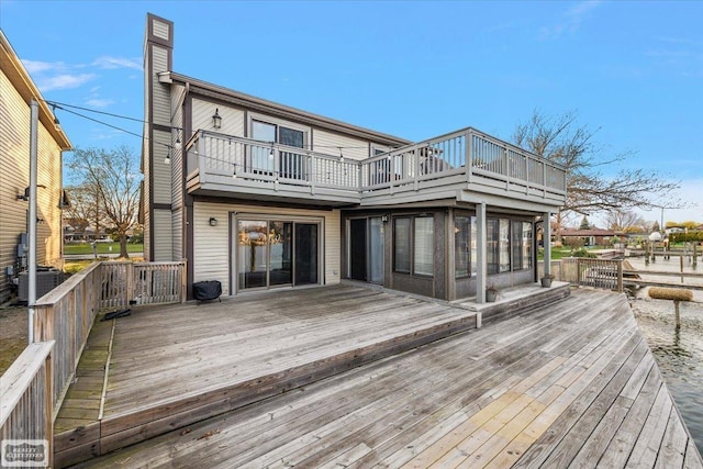 back of property with a wooden deck, a chimney, and a balcony