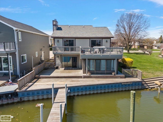 rear view of house featuring a balcony, a chimney, a yard, a deck with water view, and roof with shingles