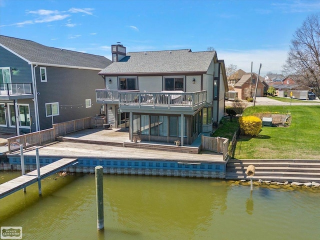 back of property featuring a chimney, a deck with water view, a residential view, and a yard