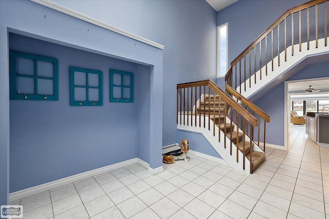 staircase with baseboards, tile patterned floors, baseboard heating, and a ceiling fan