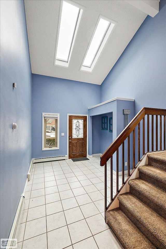foyer entrance featuring high vaulted ceiling, a baseboard radiator, stairway, a skylight, and light tile patterned floors