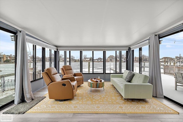 sunroom / solarium with wood finished floors and a water view