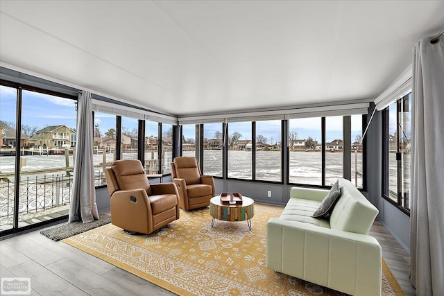 sunroom with wood finished floors and a water view