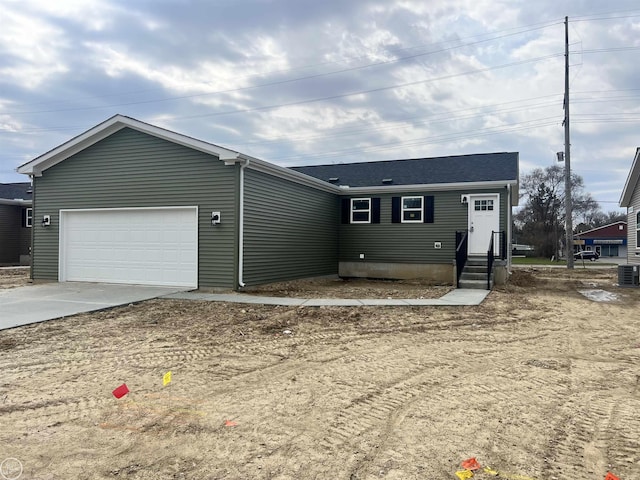 single story home featuring concrete driveway, central air condition unit, and a garage
