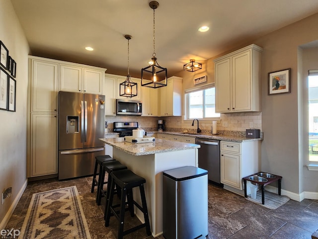 kitchen featuring a center island, baseboards, backsplash, a breakfast bar, and appliances with stainless steel finishes