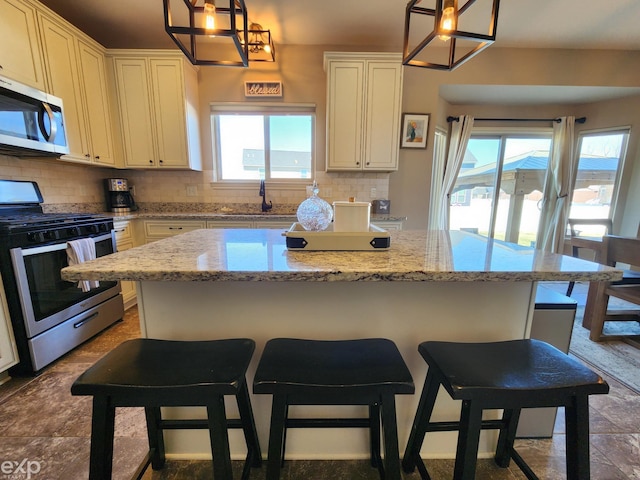 kitchen with a kitchen breakfast bar, stainless steel appliances, a sink, a center island, and tasteful backsplash