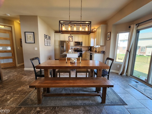 dining room with baseboards, stone finish floor, and a healthy amount of sunlight