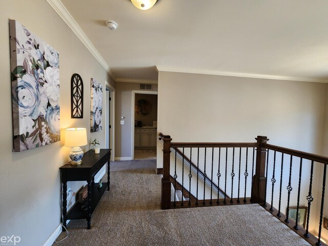 corridor featuring visible vents, ornamental molding, an upstairs landing, baseboards, and carpet flooring