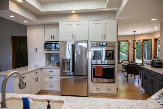 kitchen with recessed lighting, light stone countertops, appliances with stainless steel finishes, and a sink