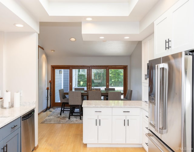kitchen with white cabinets, recessed lighting, light stone countertops, a peninsula, and appliances with stainless steel finishes